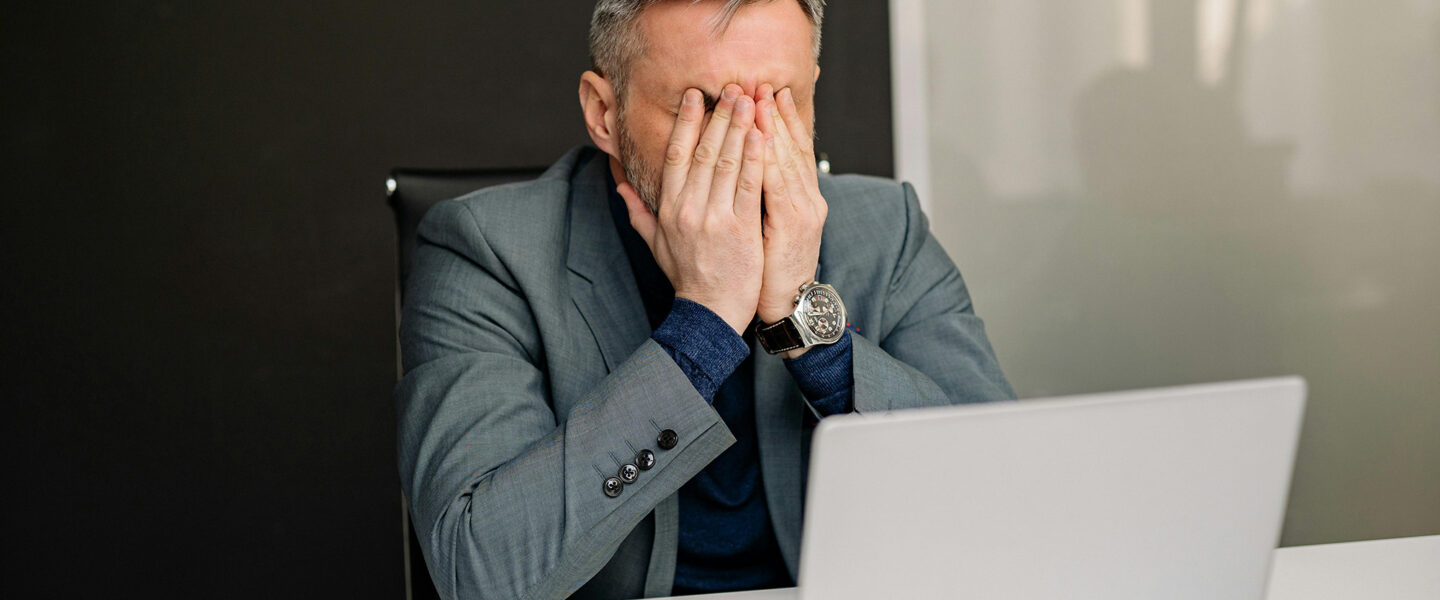 Frustrated man, covering face, laptop