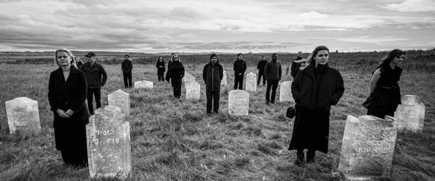 People, dressed in black, standing in a cemetery