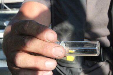 Captain Evan Clark, jar containing nurdles, water pollution